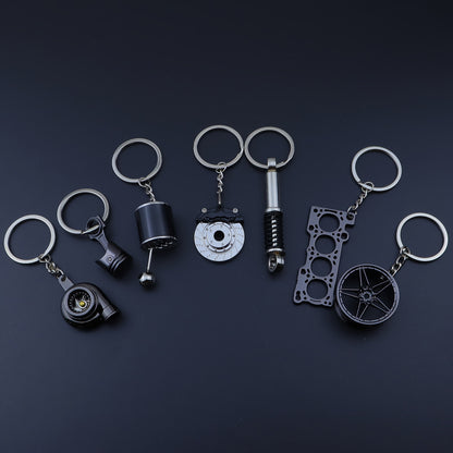 🗝️ 7-częściowy zestaw breloków tuningowych – Piston, Turbo, Wheel Hub, Gear Shift, Shock Absorber, Brake Disc, Engine Block – czarny, zinc alloy